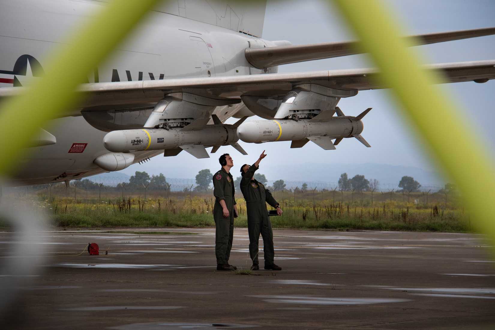 Lt. Murphy Davis (left) and Lt. Christian Hughes, assigned to Patrol Squadron (VP) 47, inspect an AGM-84D Harpoon Anti-ship Missile, on a P-8A Poseidon