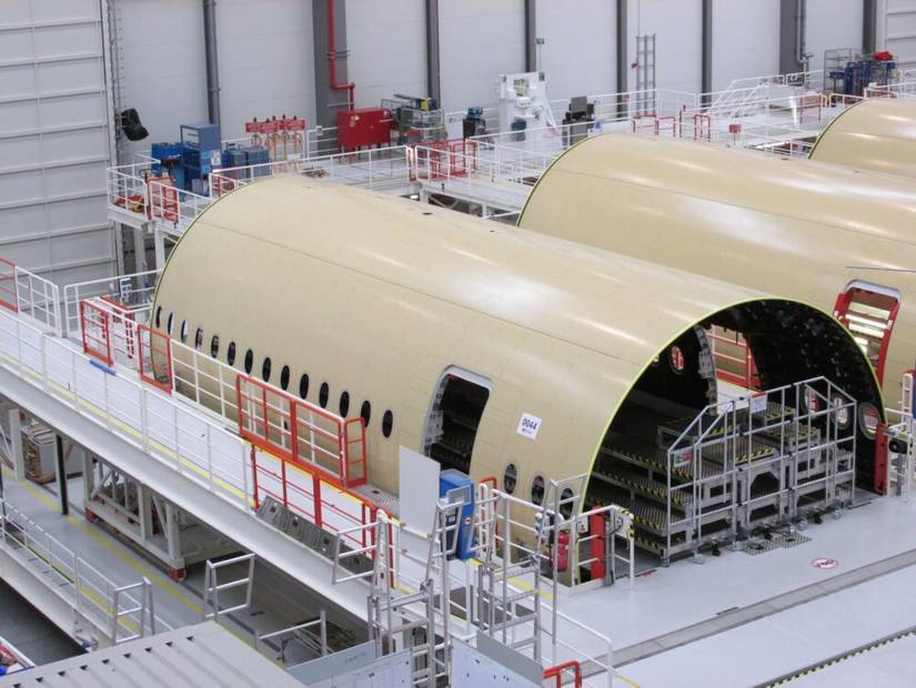 Multiple Airbus A350 fuselage pieces being assembled in a factory.