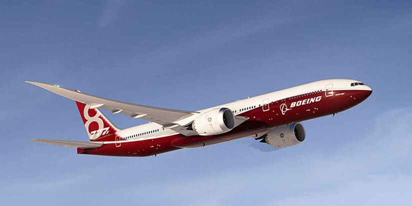 A Boeing 777-8 in red house livery flying in the sky.