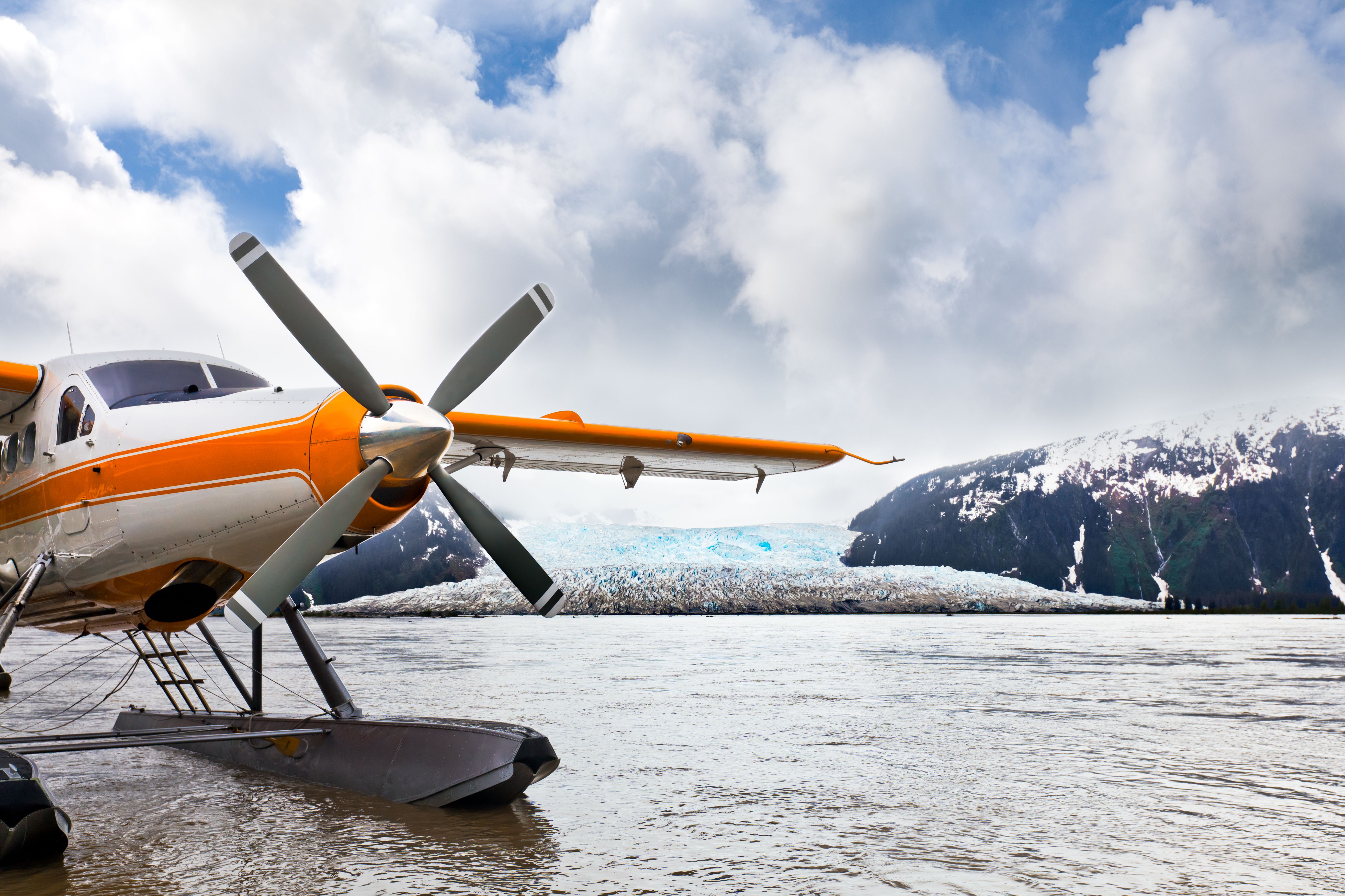 Seaplane or float plane in Alaska. The plane has landed under stormy skies near a glacier.