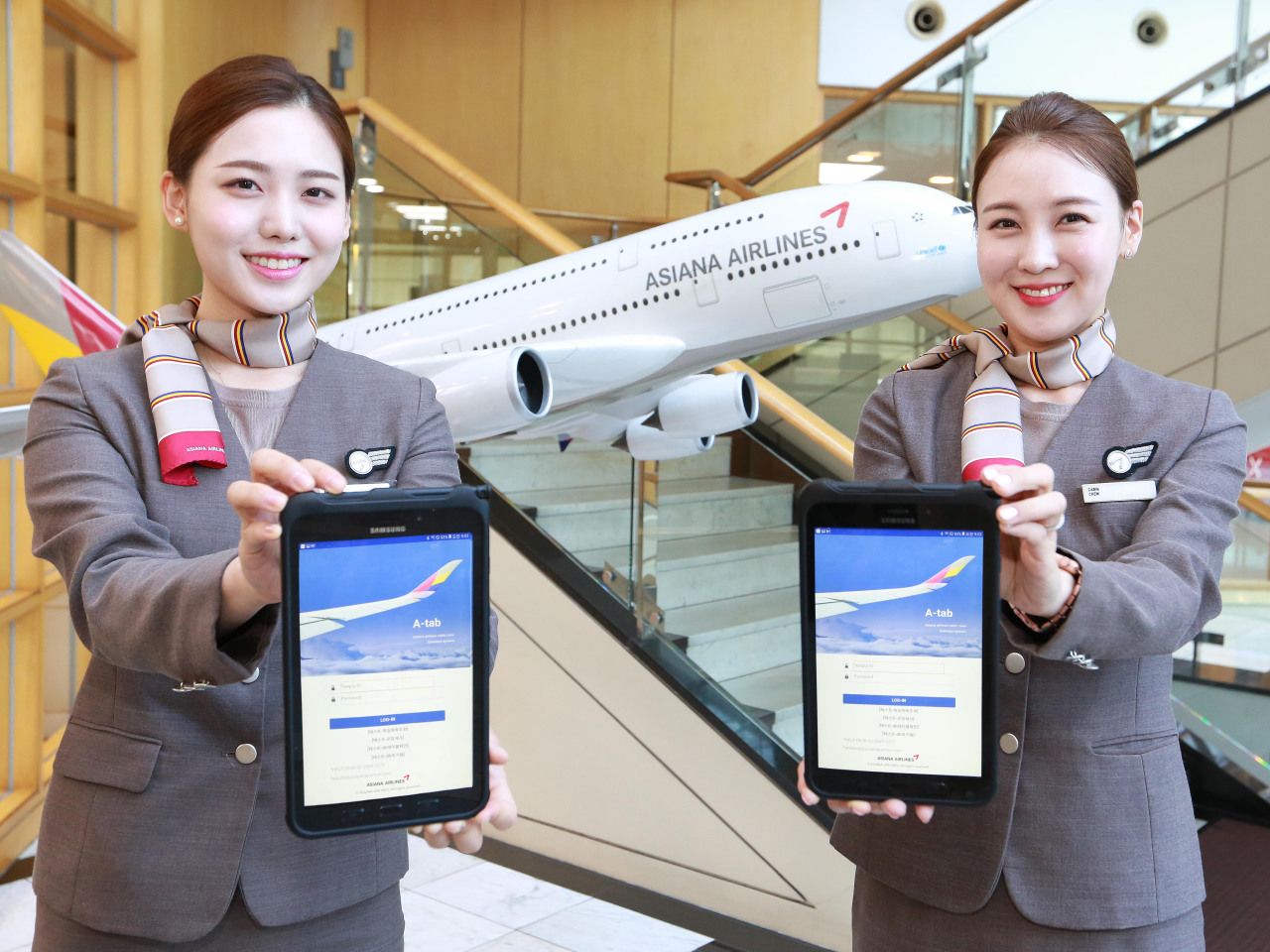Asiana airlines flight attendants holding tablets.