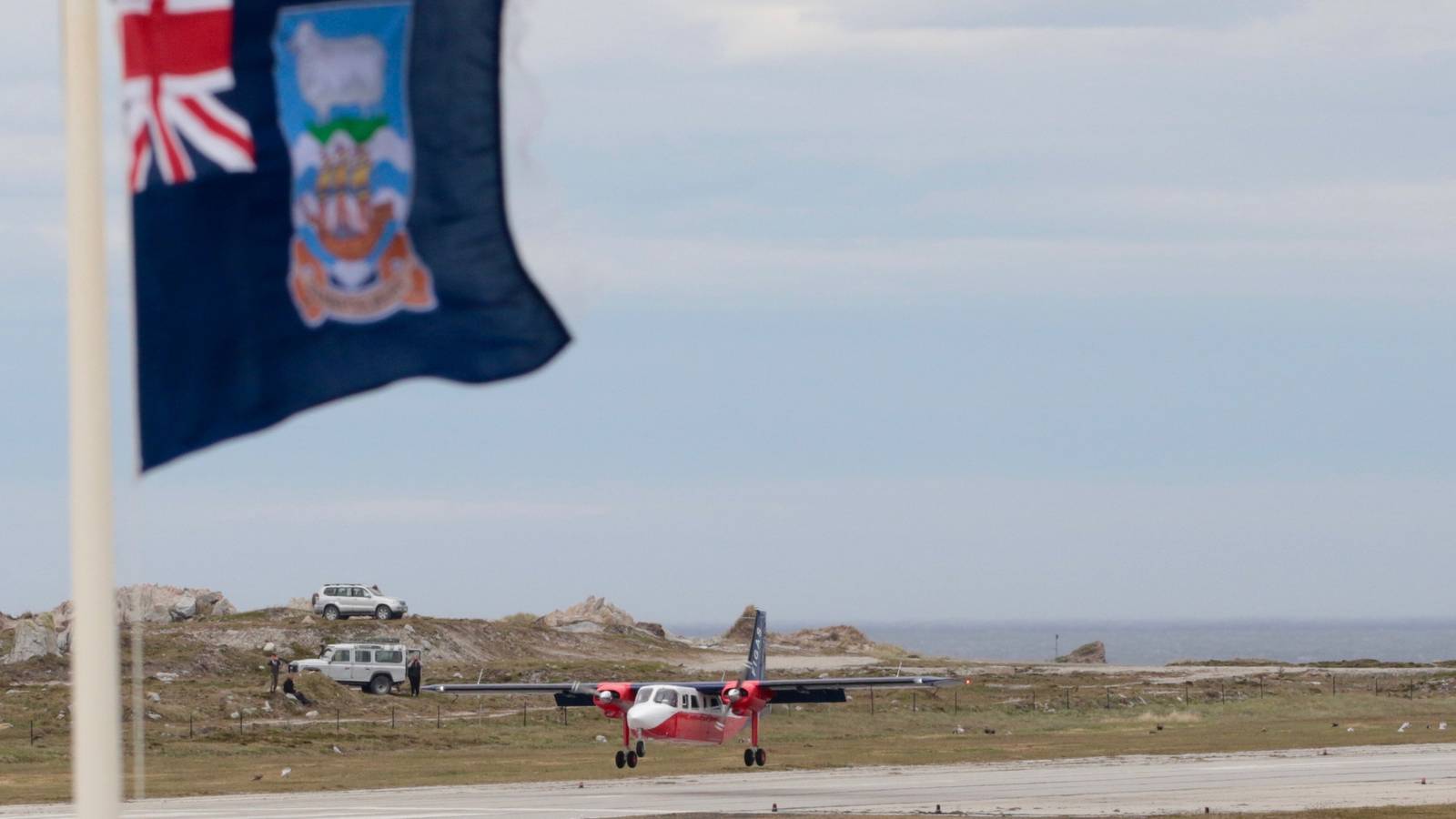 FIGAS plane on runway in Falkland Islands with flag in foreground