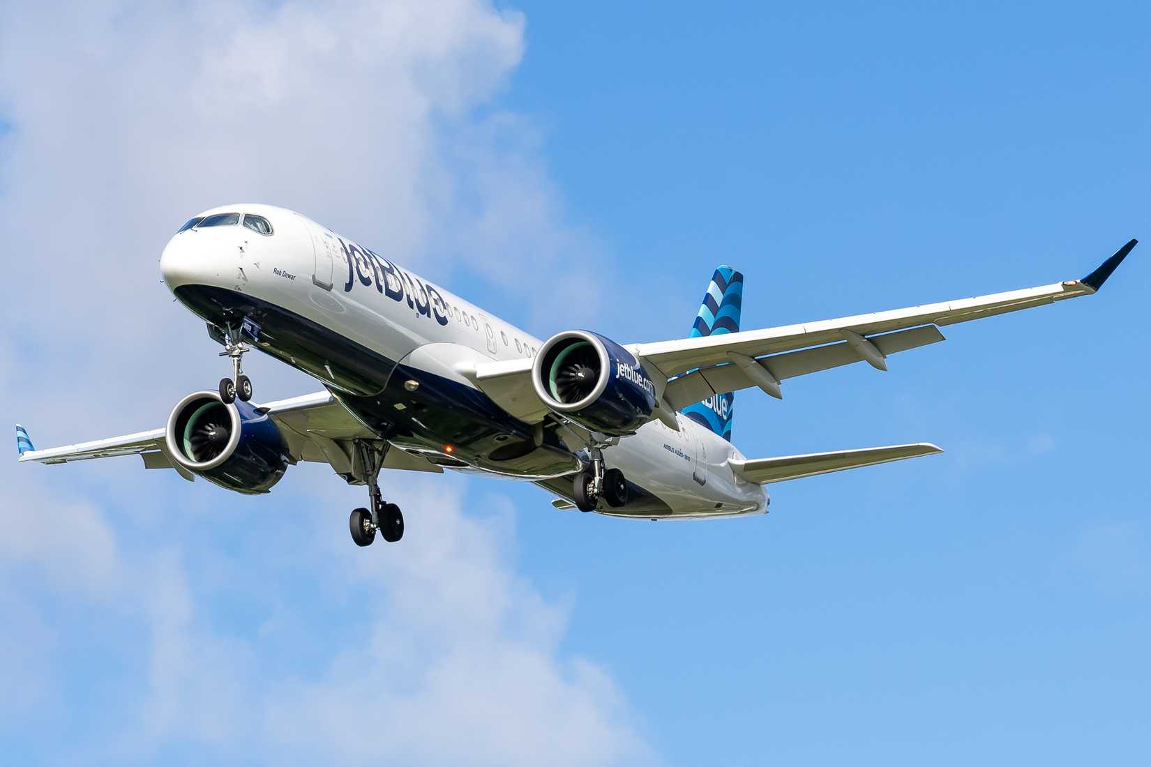 JetBlue Airbus A220 flying in the sky.
