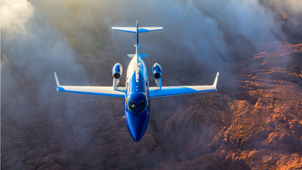 A HondaJet HA-420 flying over mountainous terrain.