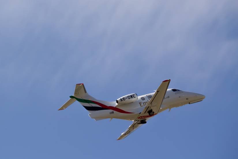 An Emirates Phenom 100EV flying in the sky.