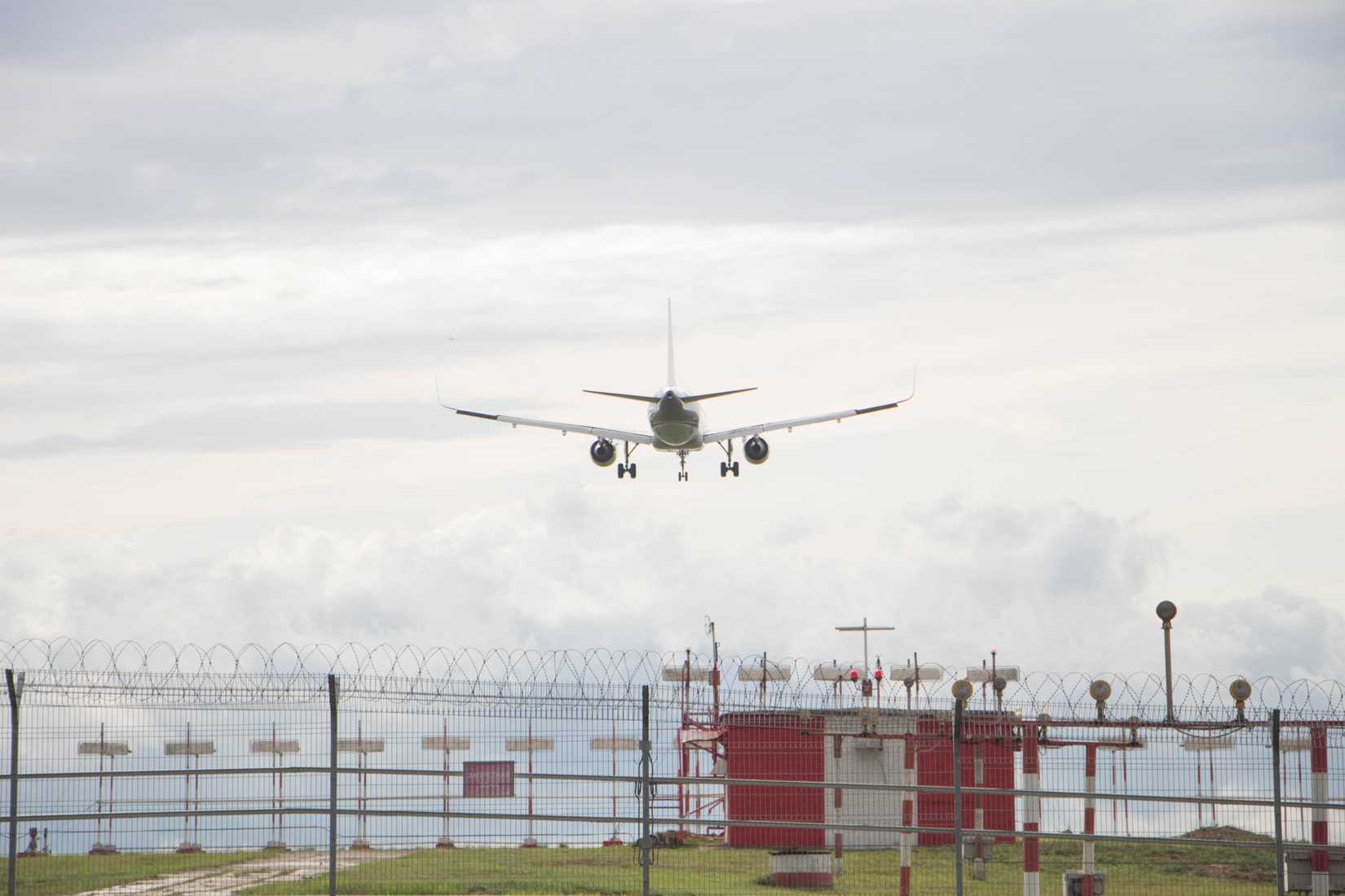 An Aircraft lands in the background ahead of an ILS system.