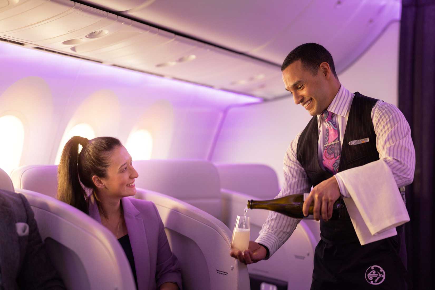 Air New Zealand Flight attendant serving wine to passenger in Business Premier-0005692