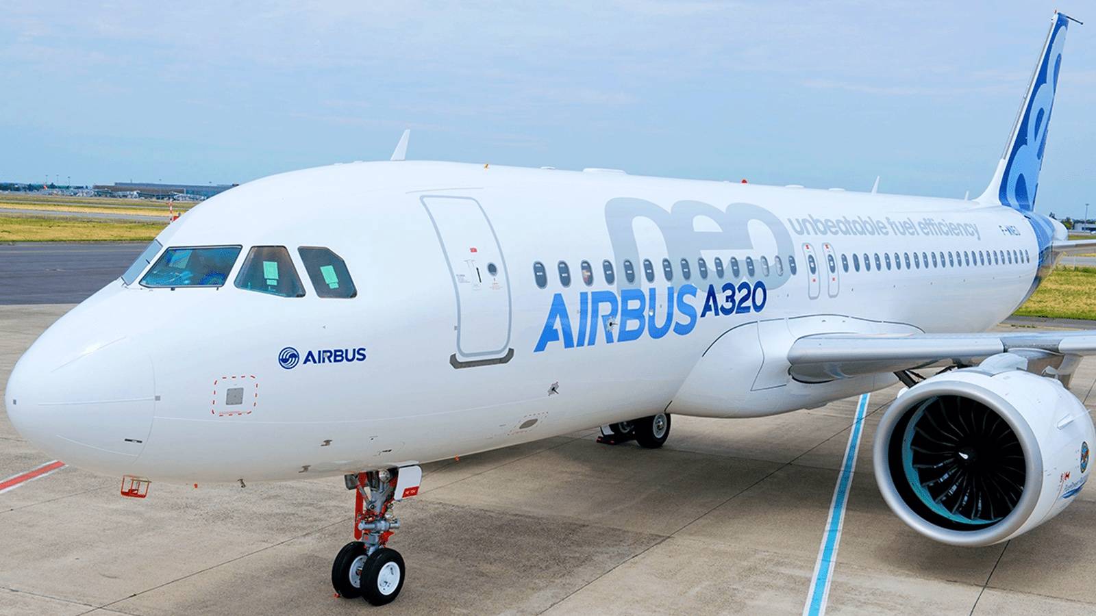 An Airbus A320neo in house livery parked at an airport.