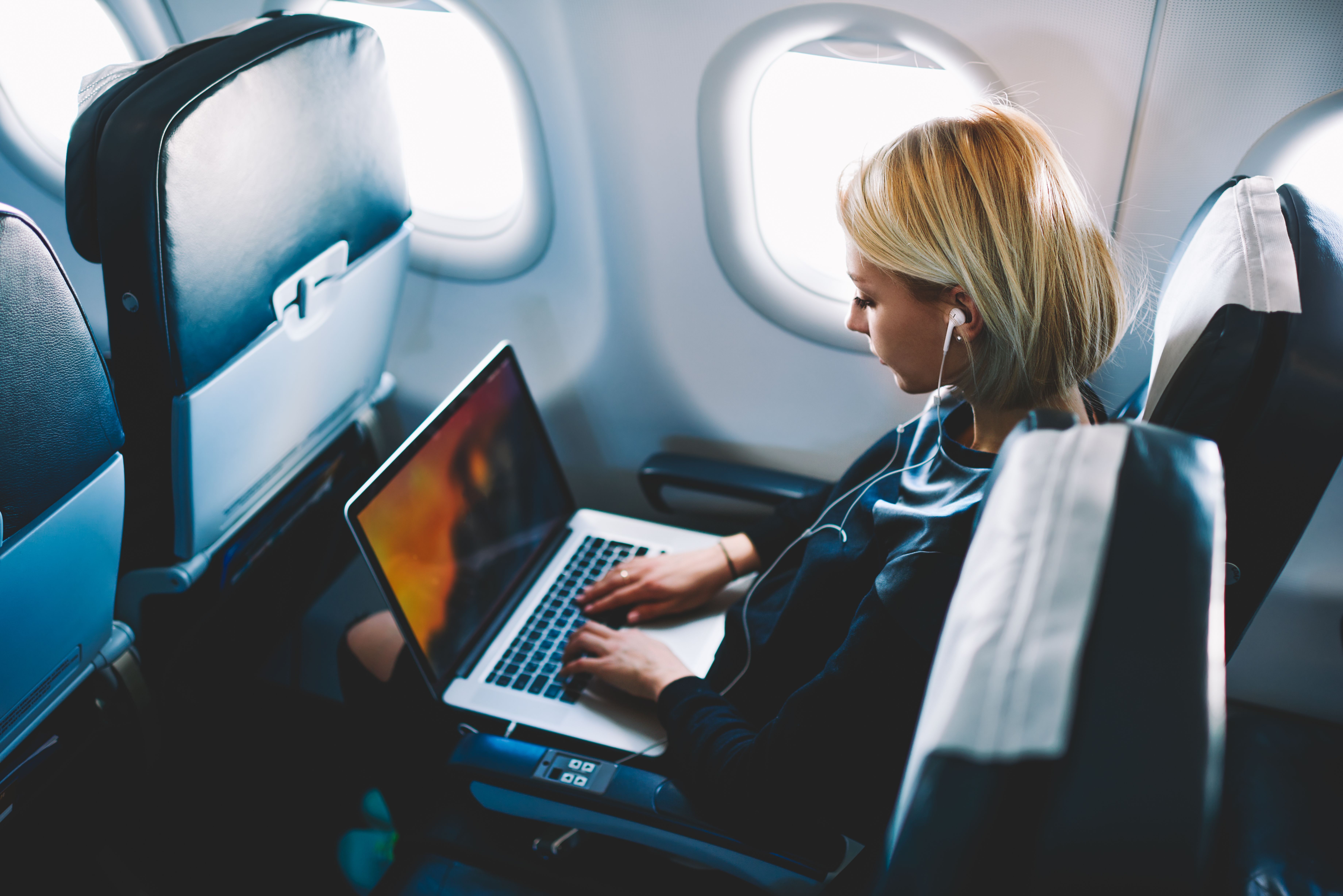 A woman using her laptop on an airplane.