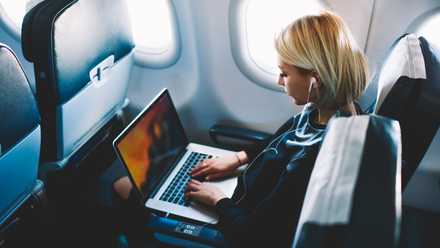 A woman using her laptop on an airplane.