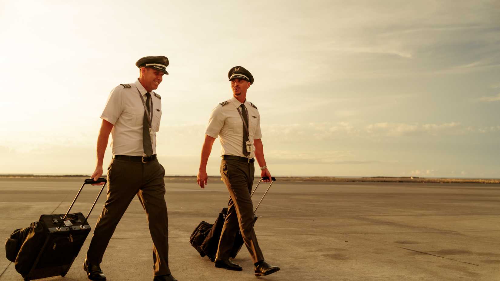 Two Hawaiian Airlines captains walking on an airport apron.