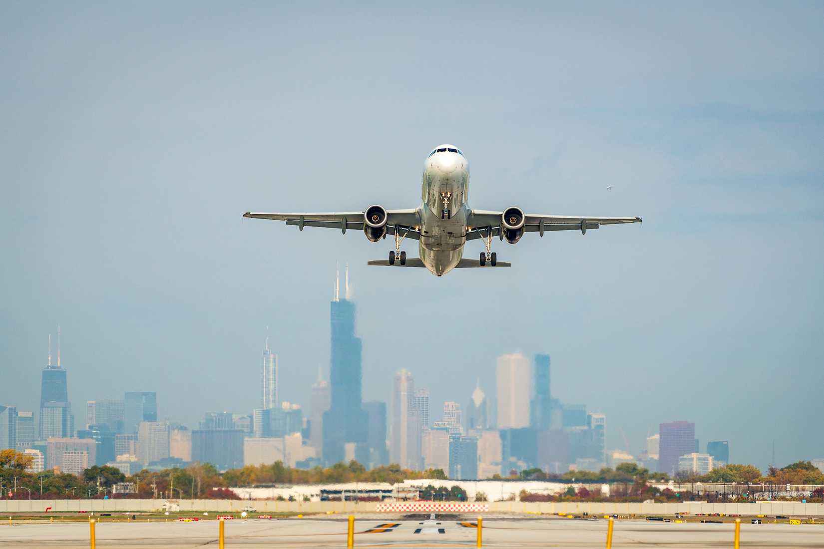 An aircraft taking off with the Chicago skyline in the background.