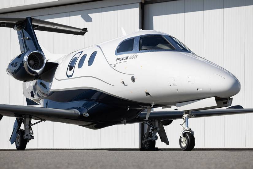 An Embraer Phenom 100EX parked outside a hangar.