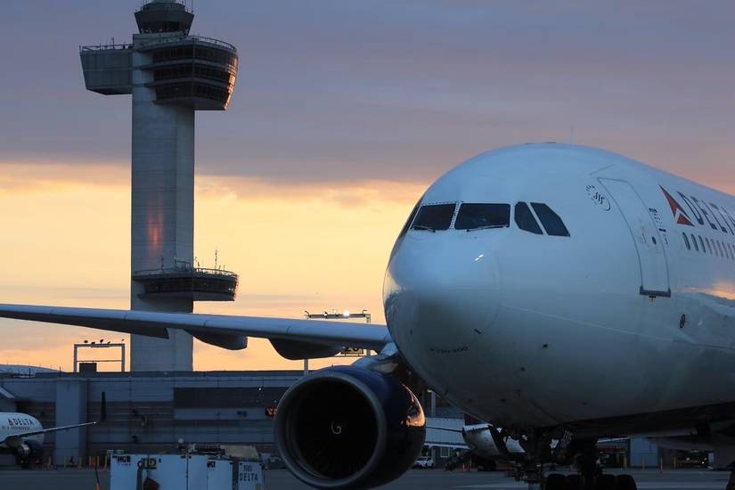 A Delta Air Lines aircraft on the JFK airport apron during sunset.
