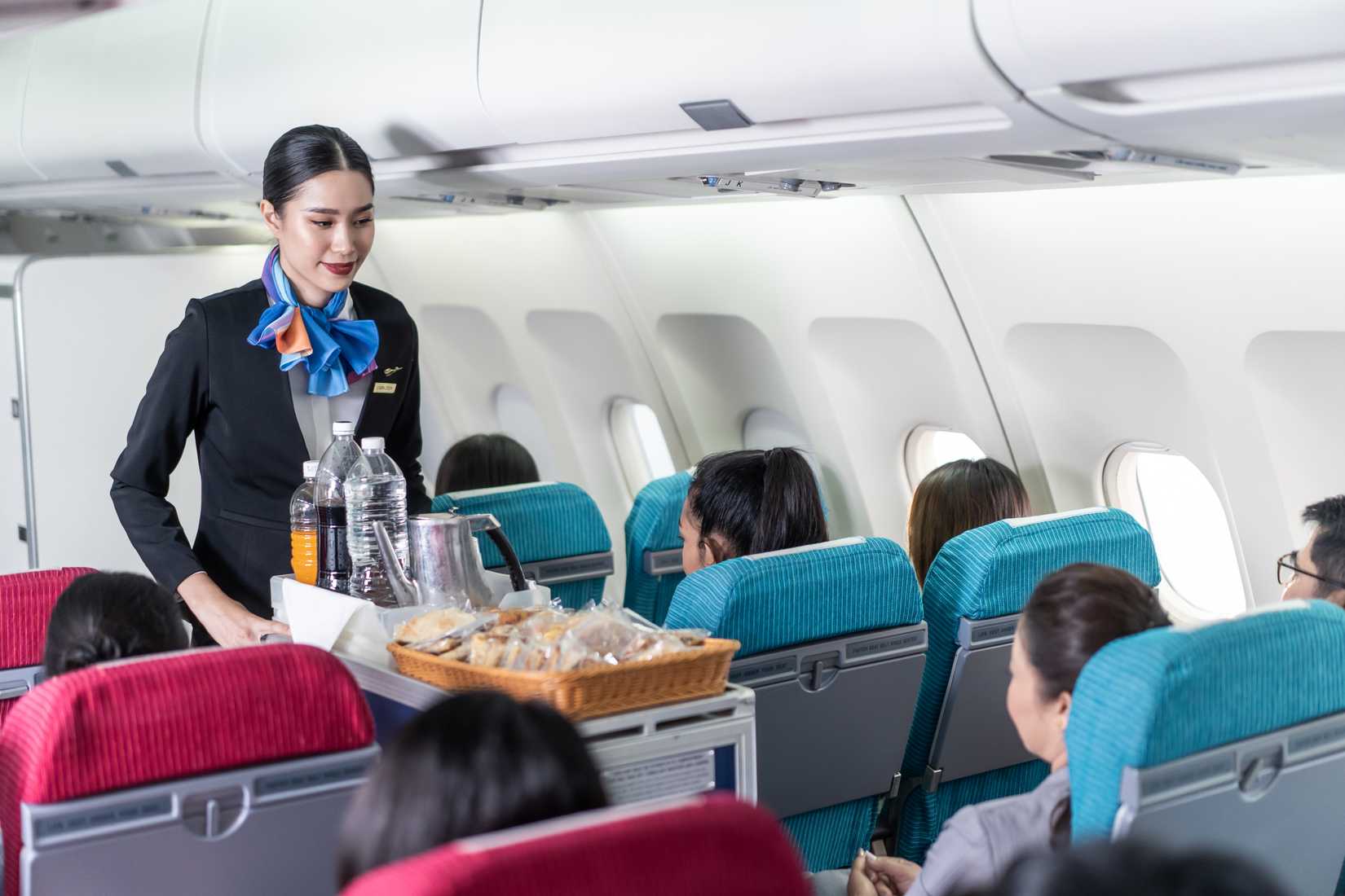 A flight attendant serving food and drink to passengers on airplane