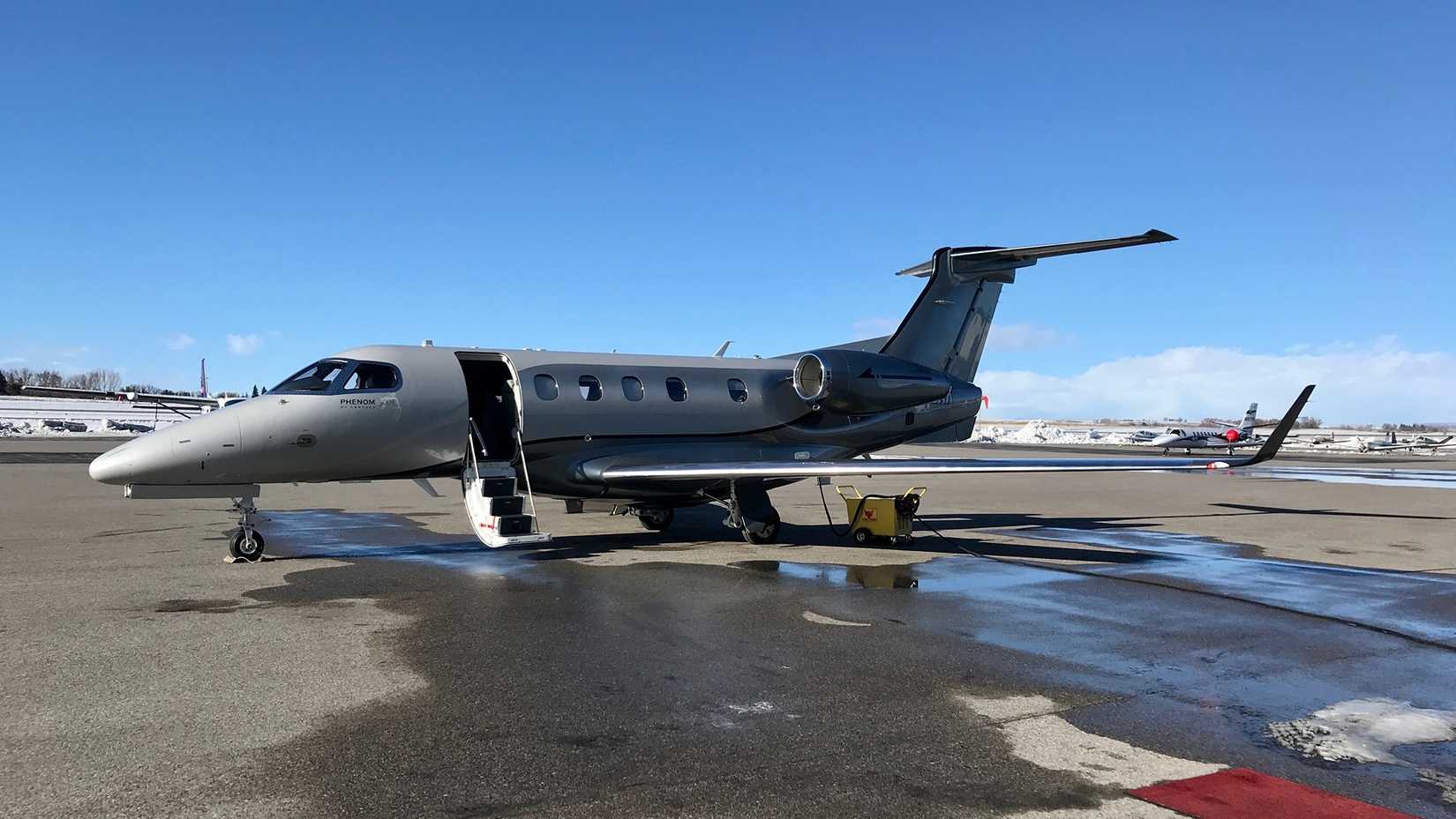 An Embraer Phenom 300E parked on the airport apron.
