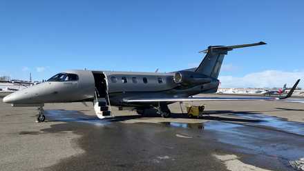 An Embraer Phenom 300E parked on an airport apron.