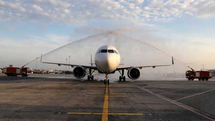 An aircraft underneath two streams of water coming from firetrucks on either side.