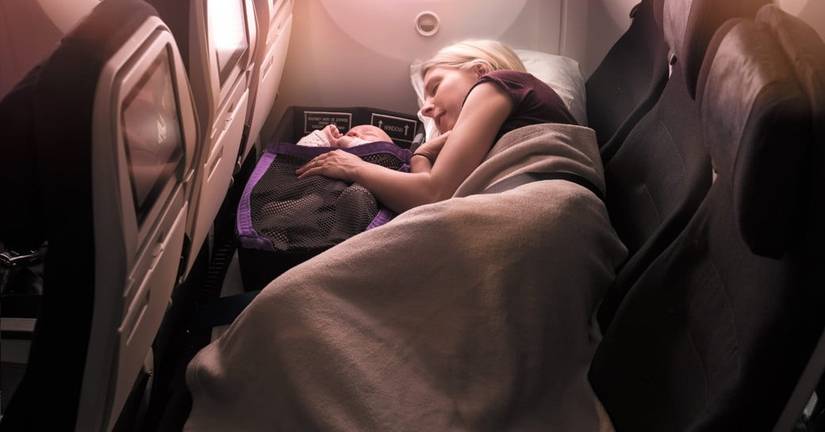 A Mother sleeping with her child in the Air New Zealand skycouch product.