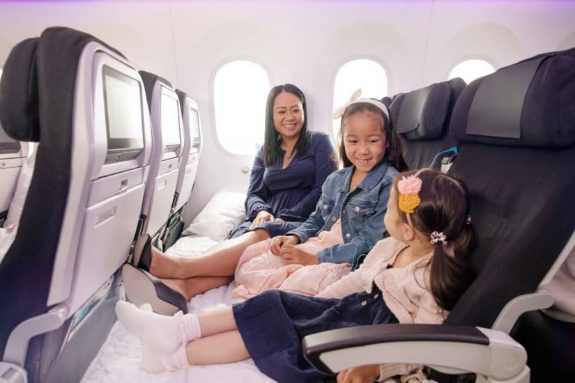 Three passengers sitting in an Air New Zealand Skycouch row.