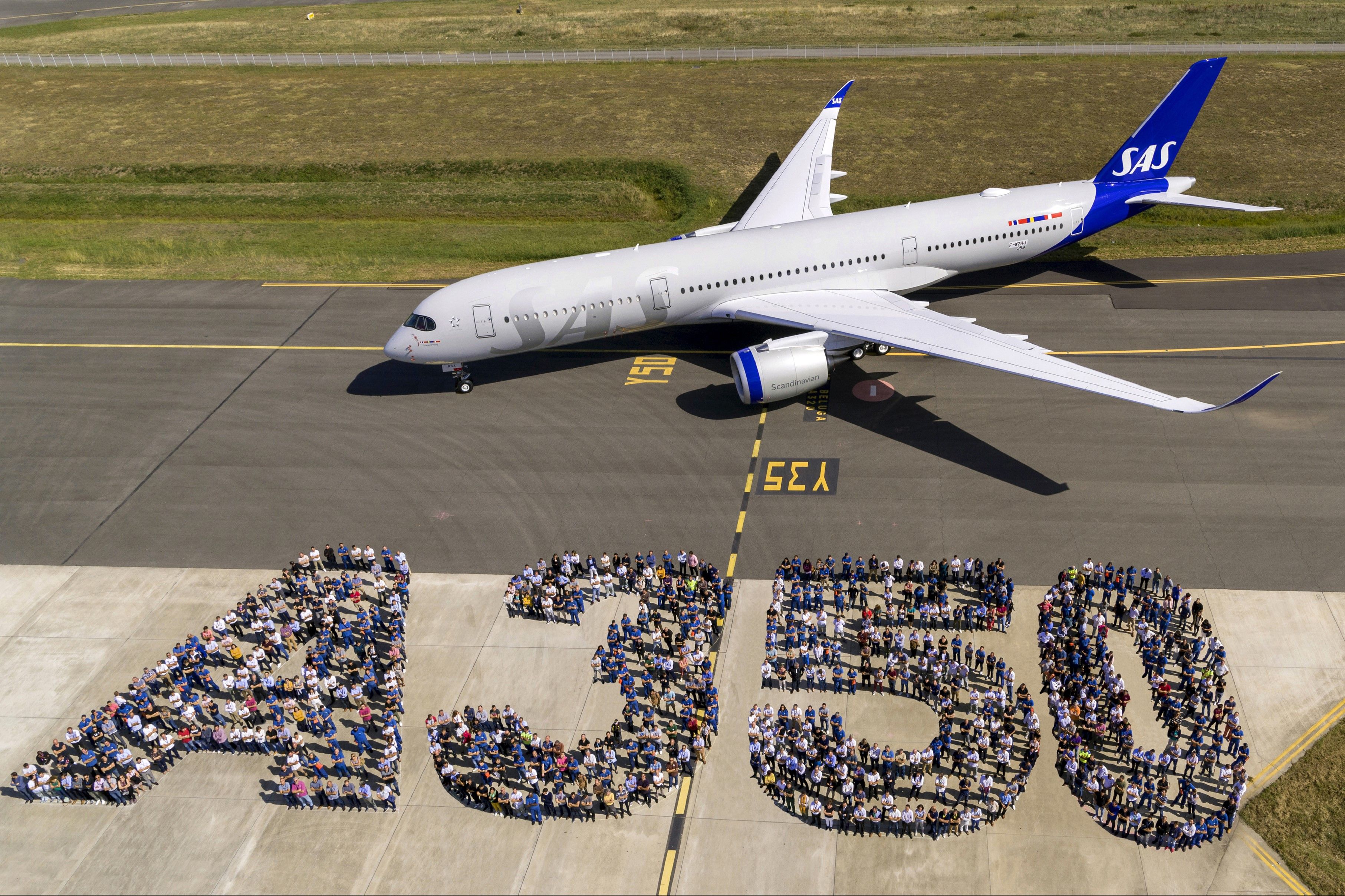 An SAS Airbus A350 on an airport apron with many employees standing in front of it.