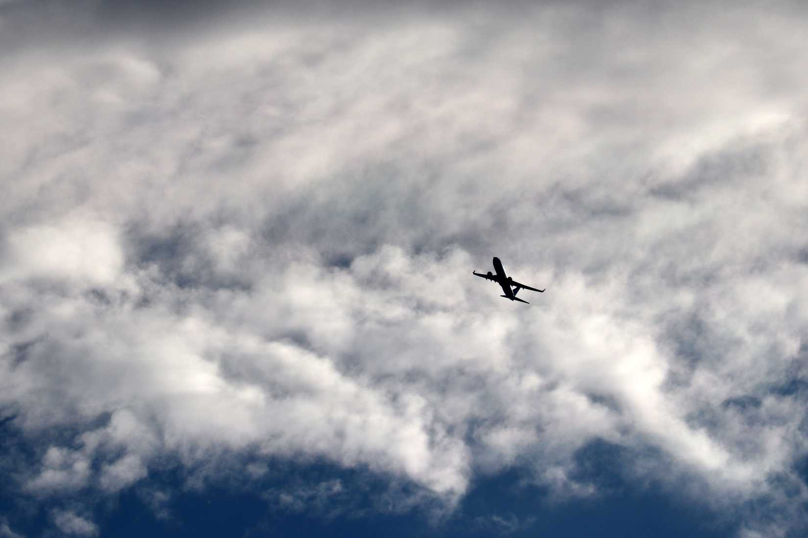 Airplane flying in the sky on background of clouds. Silhouette of a commercial plane during