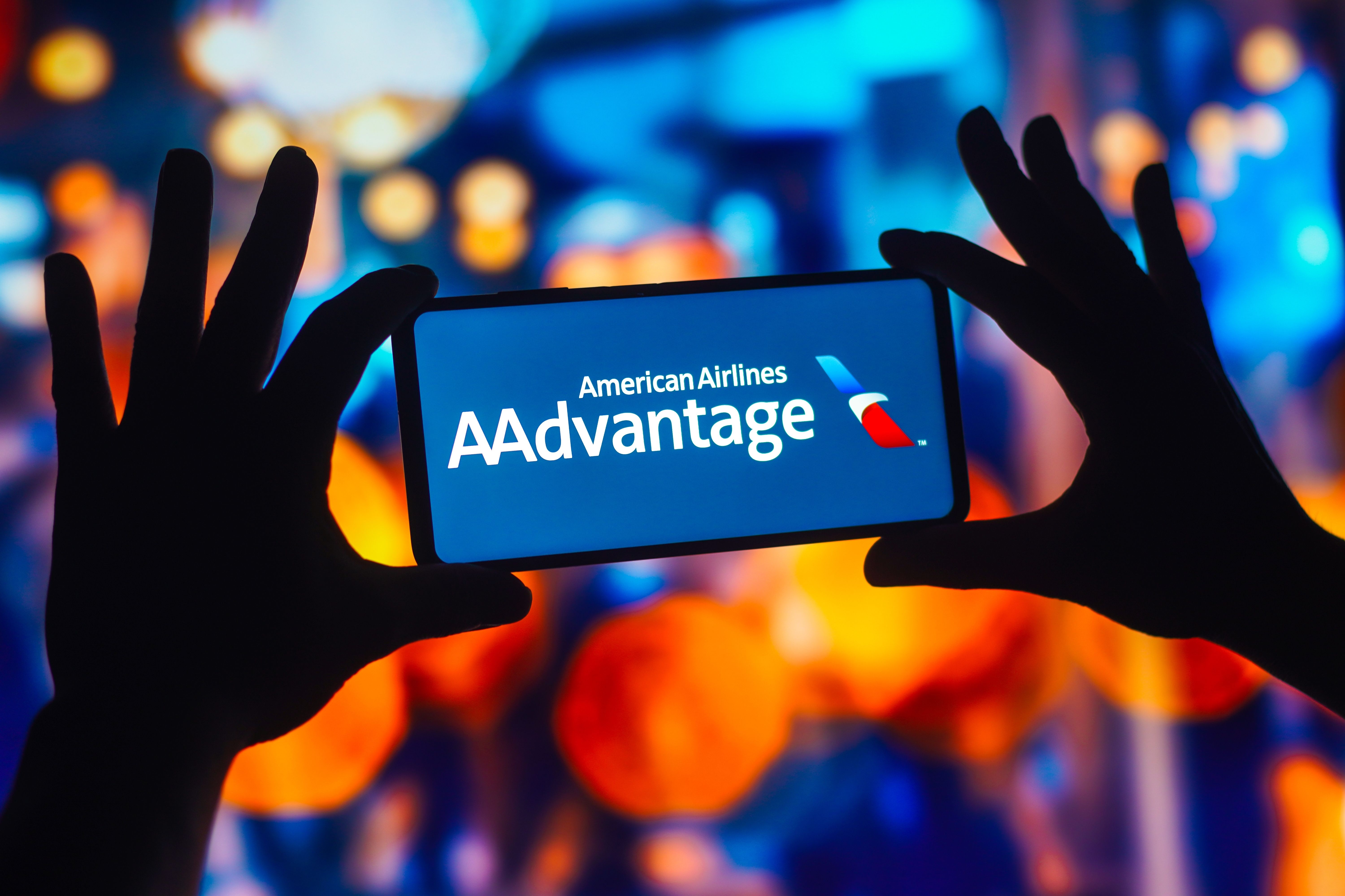 A person holding a cell phone with the American Airlines AAdvantage logo on it.