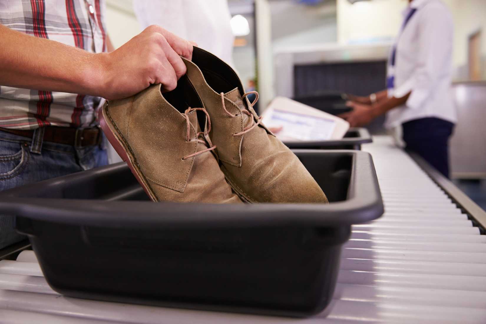 A Man Putting Shoes Into Tray For Airport Security Check 
