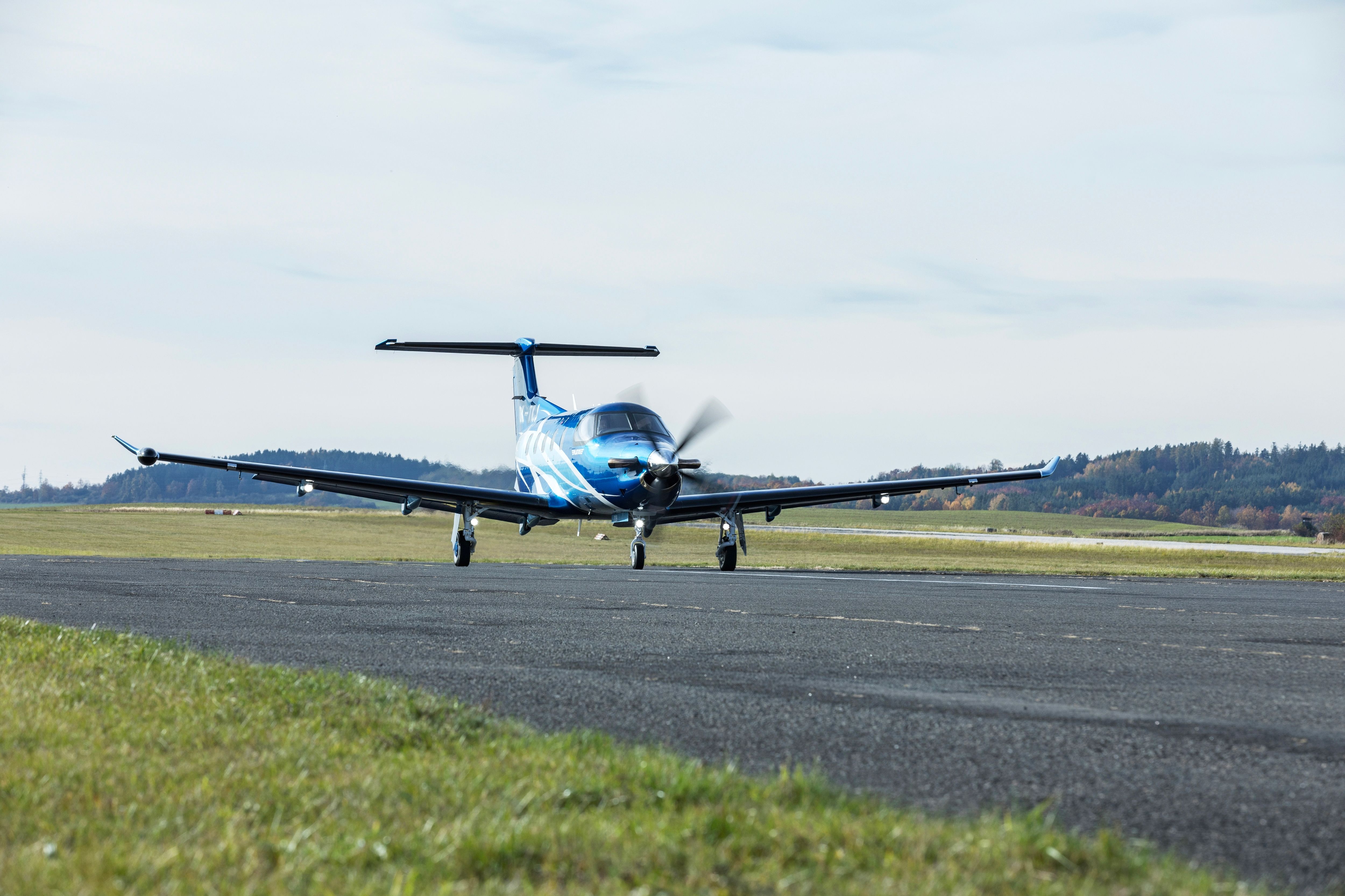 A modern Pilatus PC-12 NG turboprop aircraft takes off from a small airport