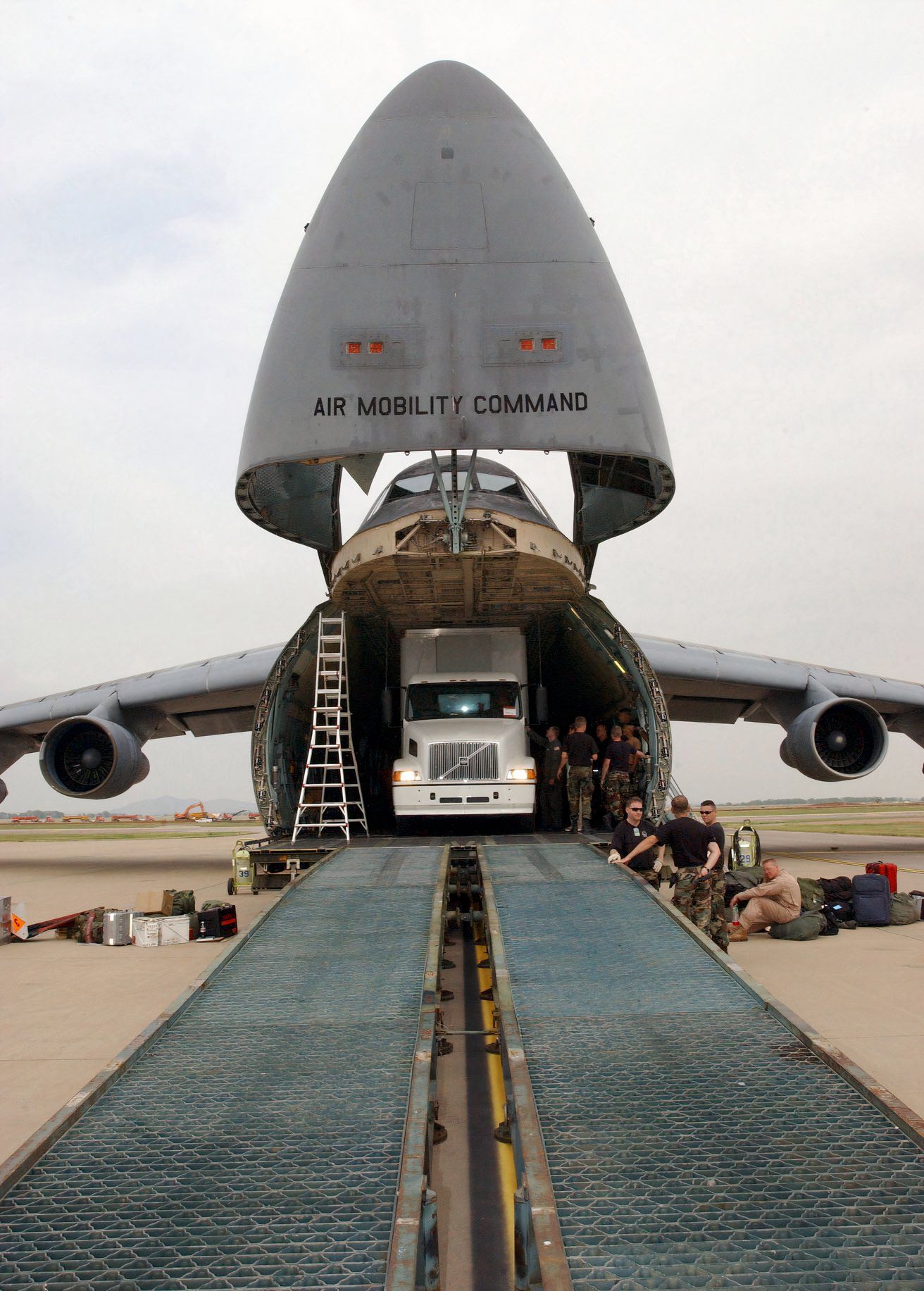 Photo of a C-17 of the 97th Air Mobility Wing unloading a semi full of humanitarian supplies.