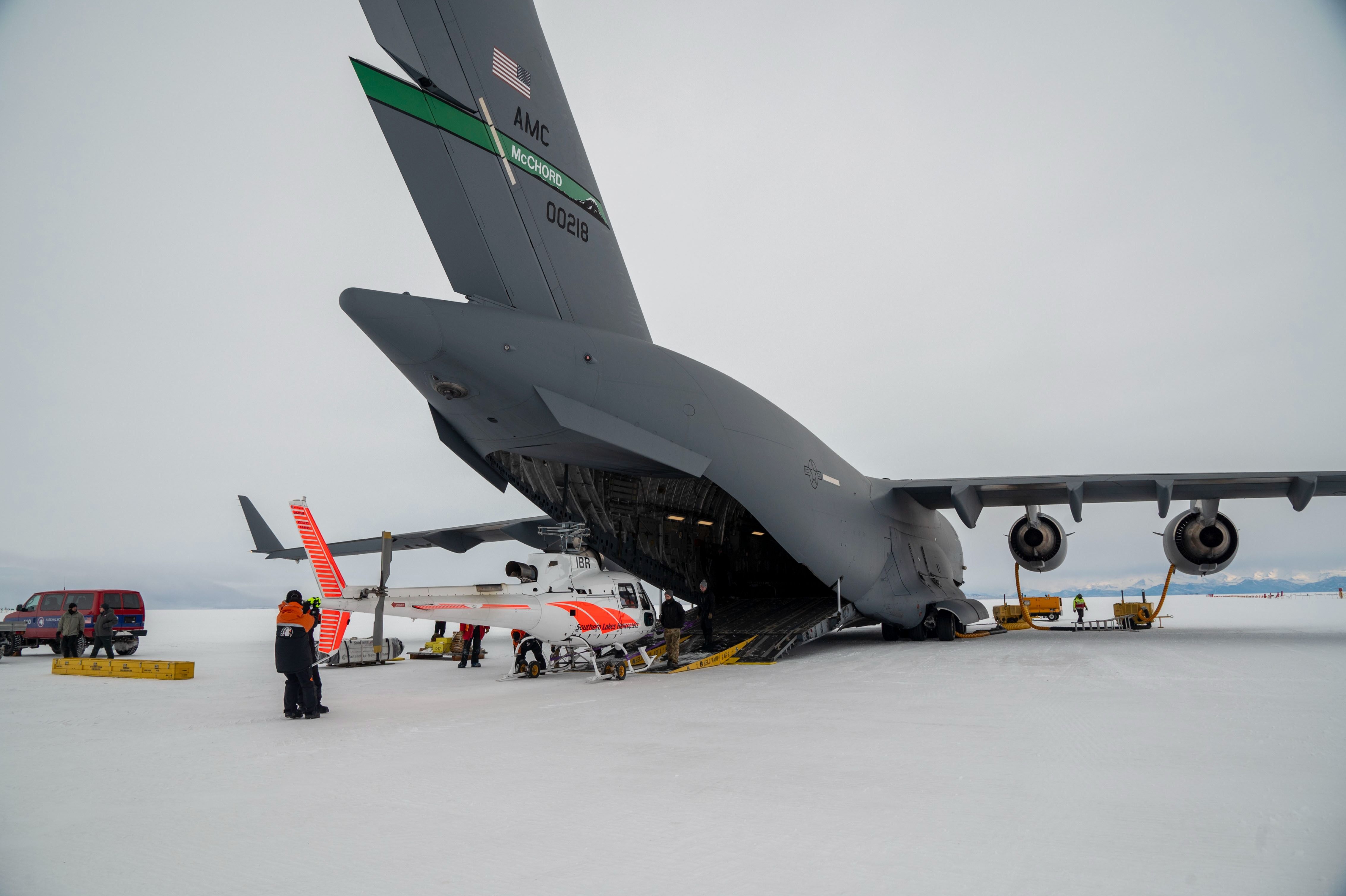 241020-F-TT585-1104 - U.S. Air Force Airmen, all loadmasters from Team McChord, lower a ramp down between the Antarctic ice and the ramp of a C-17 Globemaster III, at Phoenix Airfield, Antarctica, Oct. 20, 2024. The Helo ramp used ensured a smooth offloading for the small helicopter.