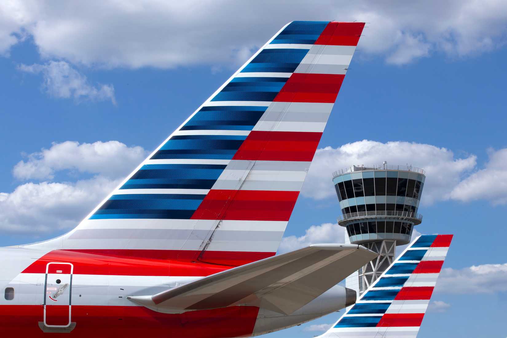 American Airlines aircraft with an ATC tower in the background shutterstock_2073219833