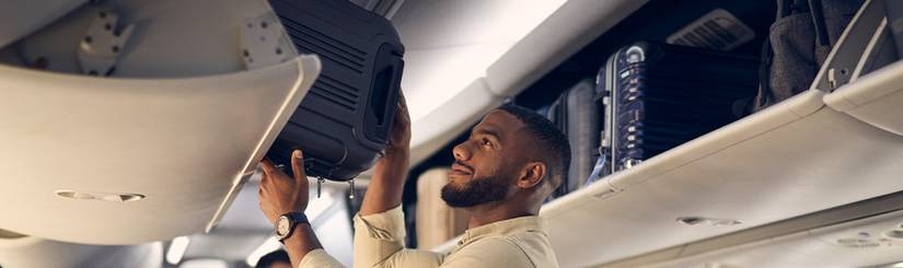 passenger loads his bag into overhead storage on American airlines