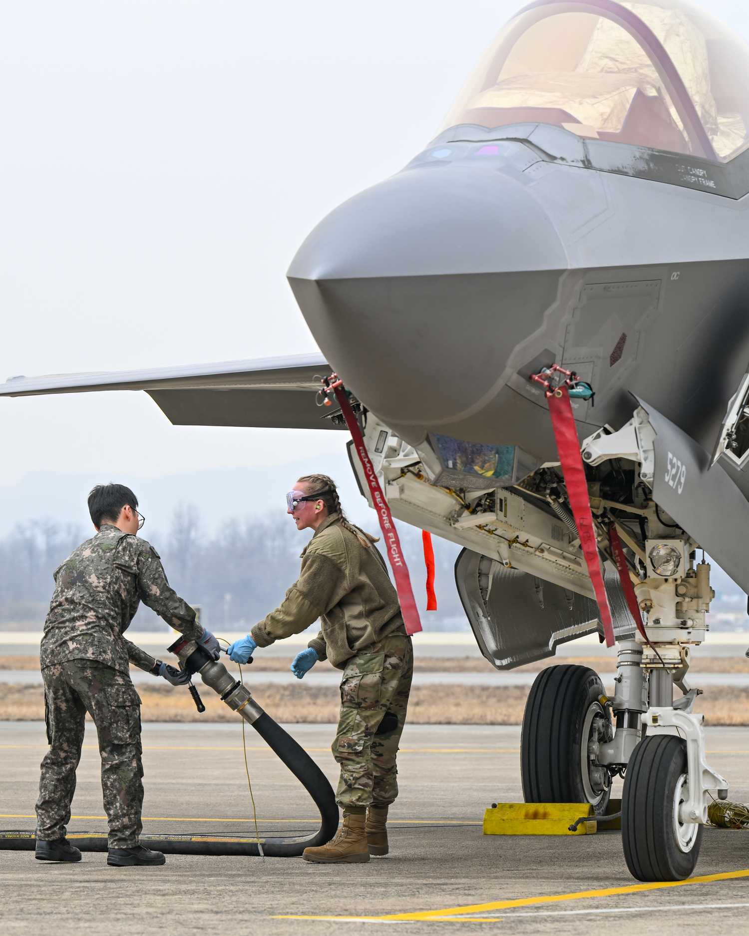 USAF Senior Airman Sydney Weber, an F-35A Lighting II crew chief with the 134th Expeditionary Fighter Squadron, Vermont Air National Guard, hands-off a fueling hose to a ROKAF member.