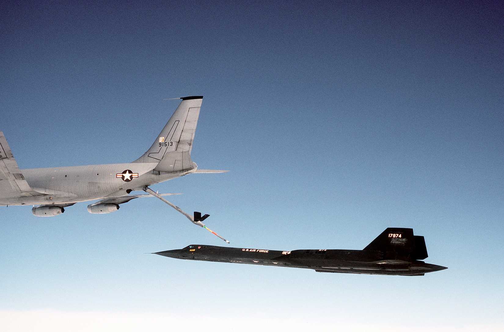 A left side view of an SR-71 aircraft moving toward a KC-135 Stratotanker aircraft for inflight refueling. The SR-71 is from the 9th Strategic Reconnaissance Wing
