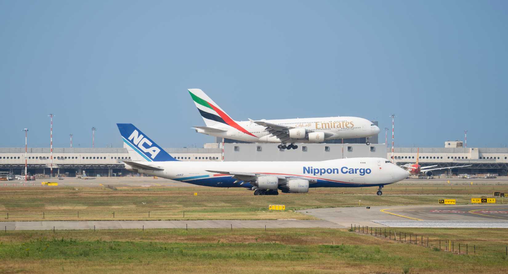NCA Nippon Cargo Airlines Boeing 747 is taxiing and Emirates A380 is landing at MXP Milano Malpensa international airport