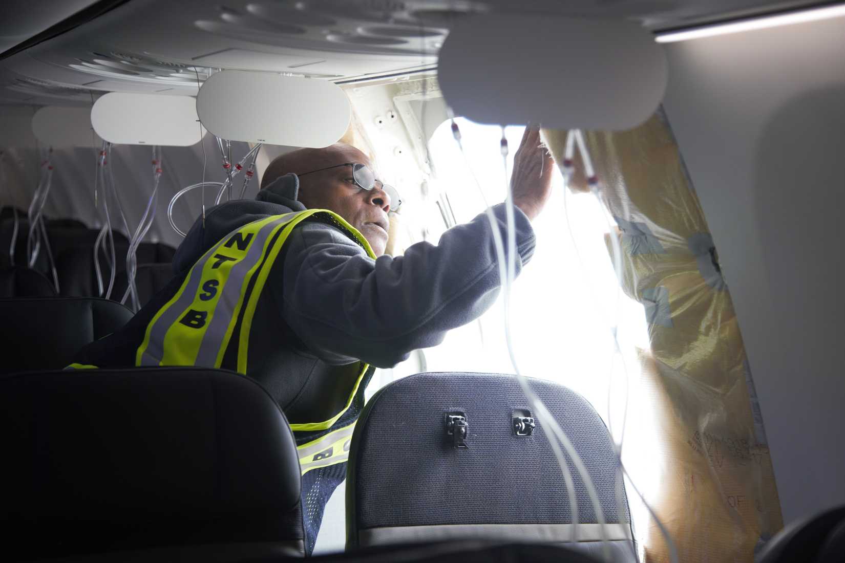 Investigator-in-Charge John Lovell examines the fuselage plug area of Alaska Airlines Flight 1282 Boeing 737-9 MAX. Captured on Jan. 7