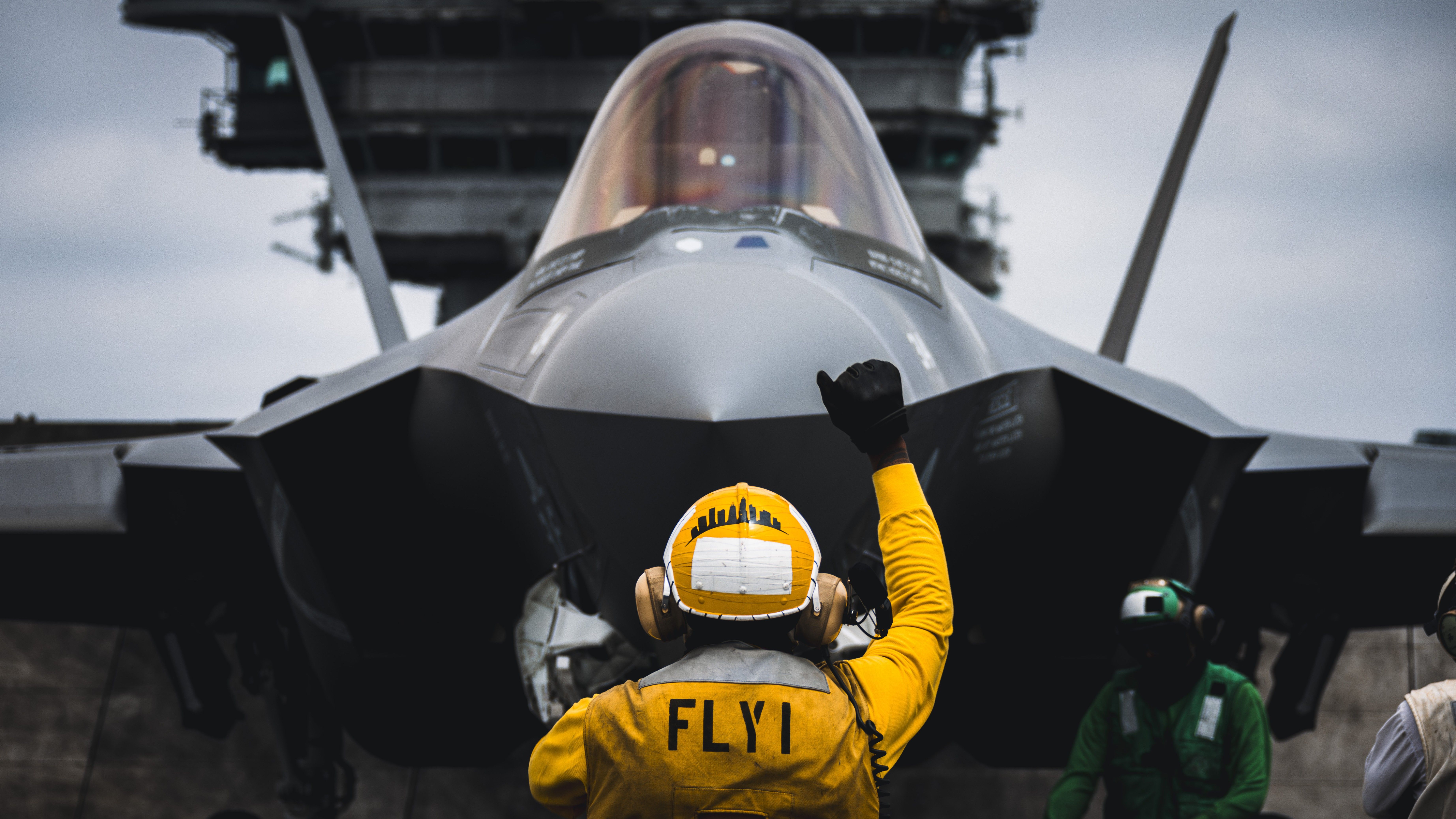 Airman signals an F-35C Lightning II to hold on the flight deck