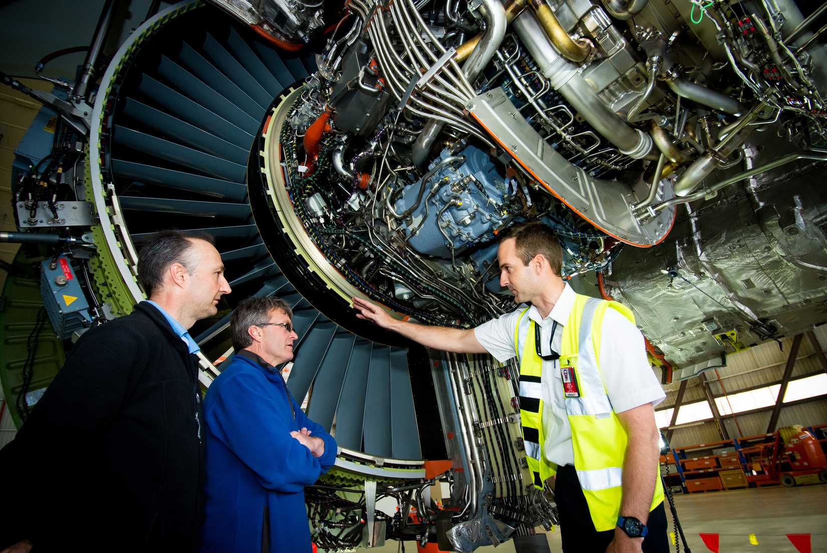 Mechanics and staff look at the internals of a 787 engine