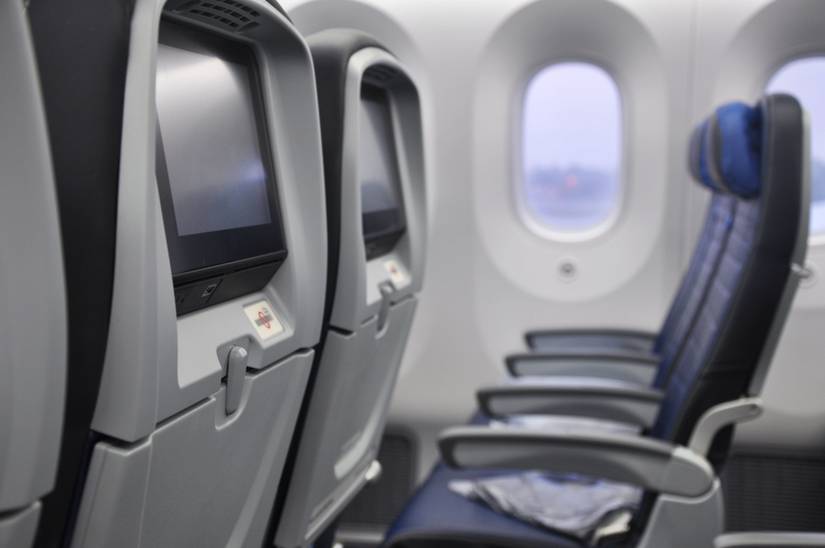 Row of empty blue leather airplane seats and window on a Boeing 787 Dreamliner