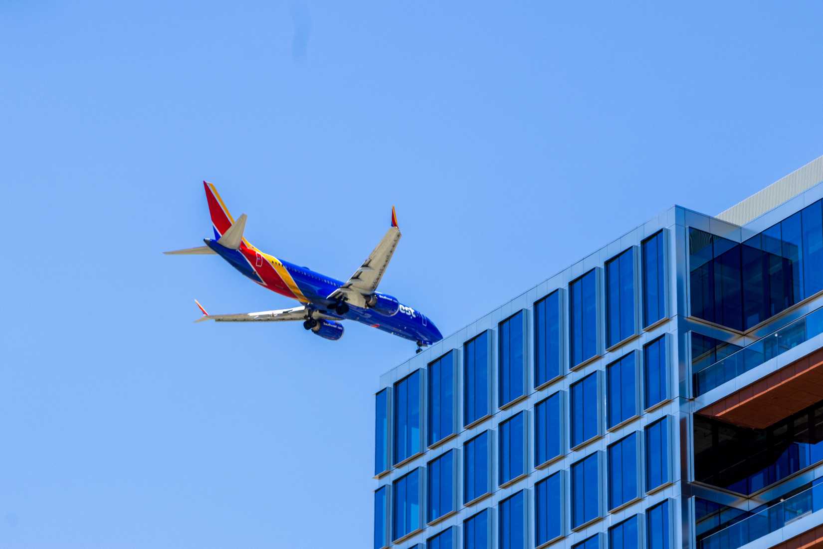 A Southwest airlines airplane flying over a building in downtown San Jose California USA