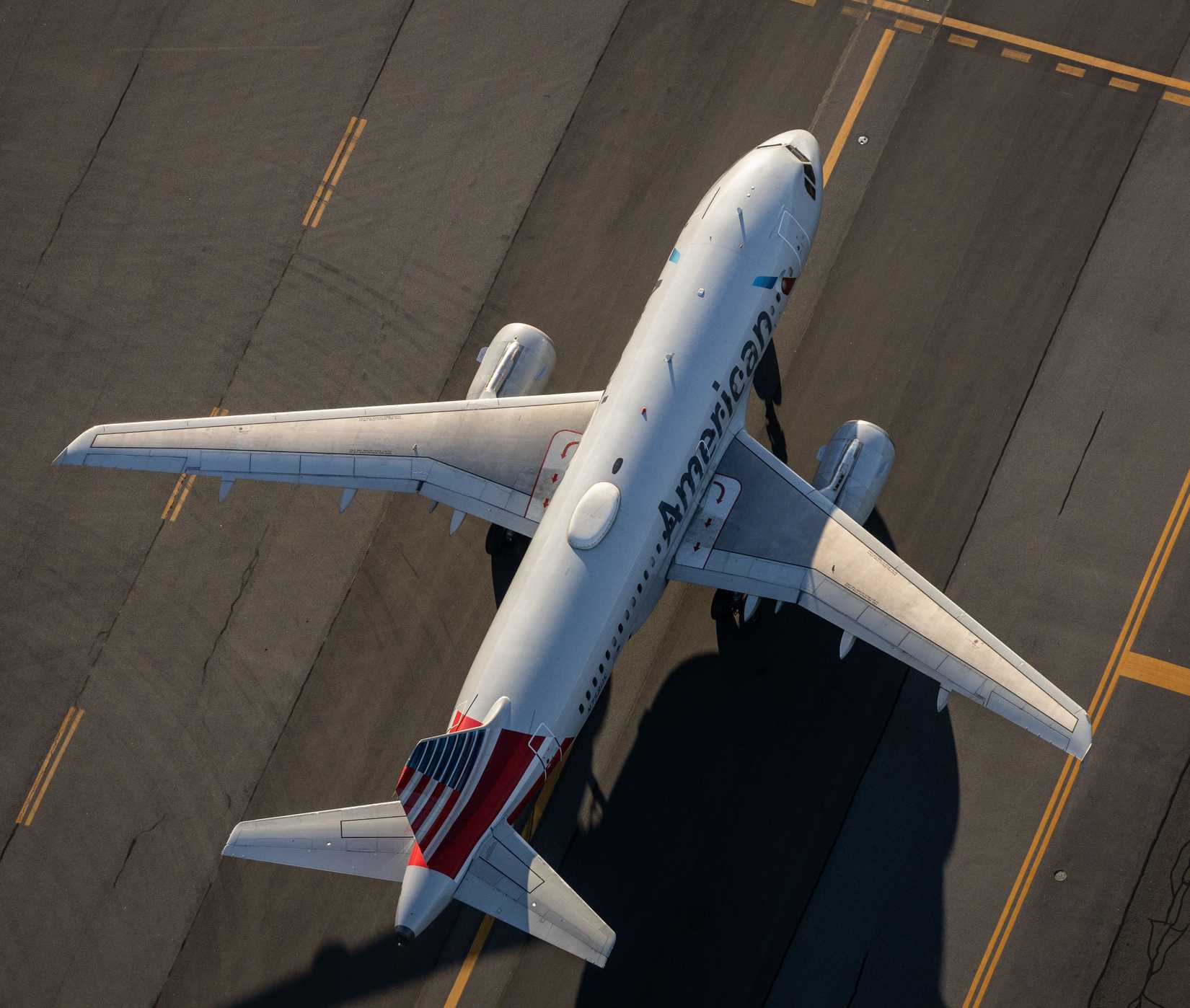 An aerial top-down view of an American Airlines plane taxiing at Boston's Logan Intersection Airport.