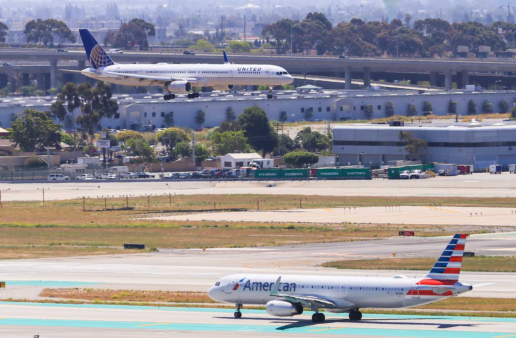 An United Airlines Boeing 757 lands at the Los Angeles International Airport (LAX). In the foreground waits an American Airlines plane for take off.