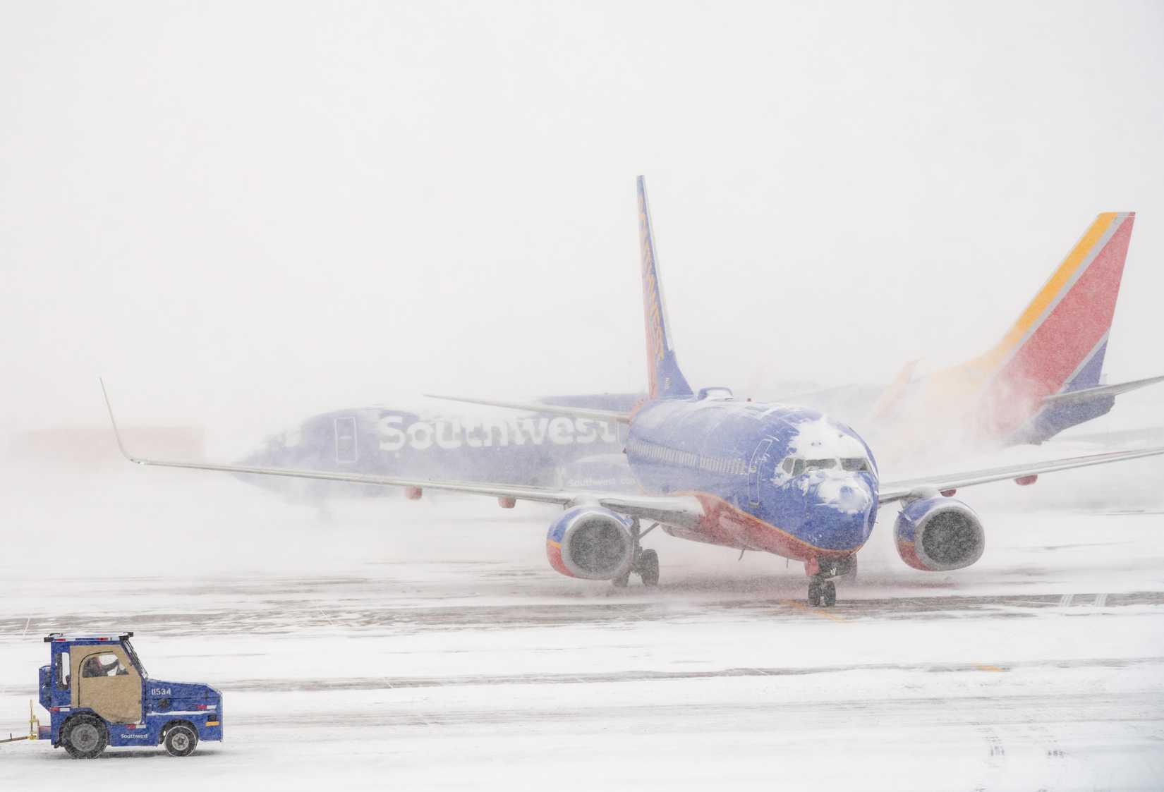 Southwest plane on runway as second one passes behind in snow storm.