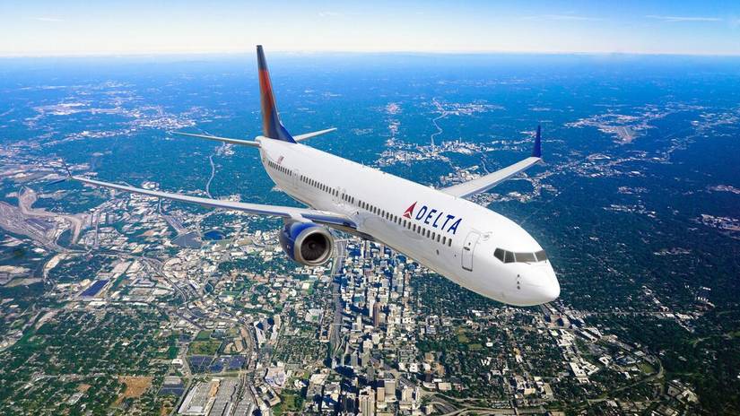 737-10 MAX aircraft in flight over a city