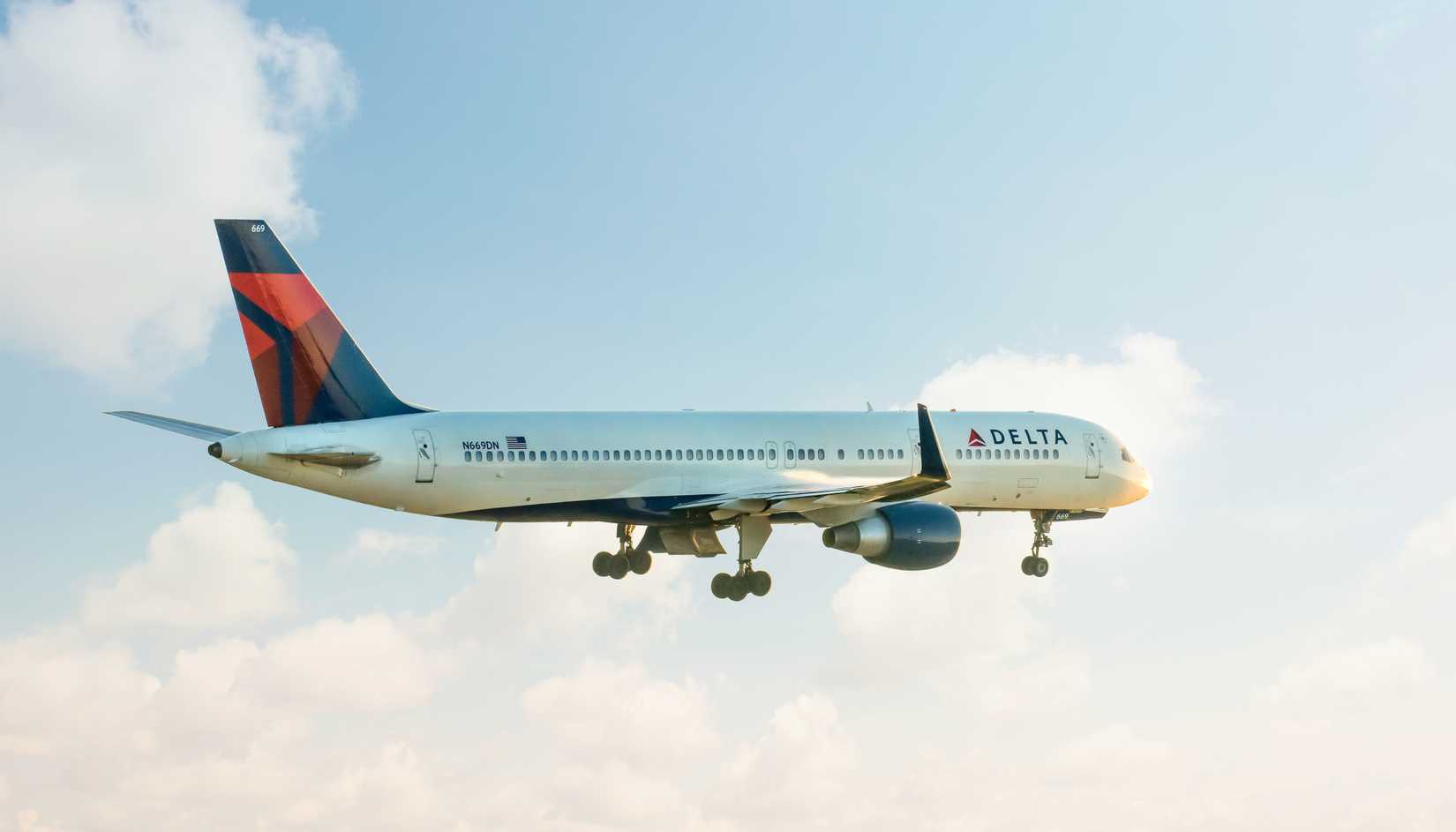 A 757-200 takes off for departure into a clouded sky.
