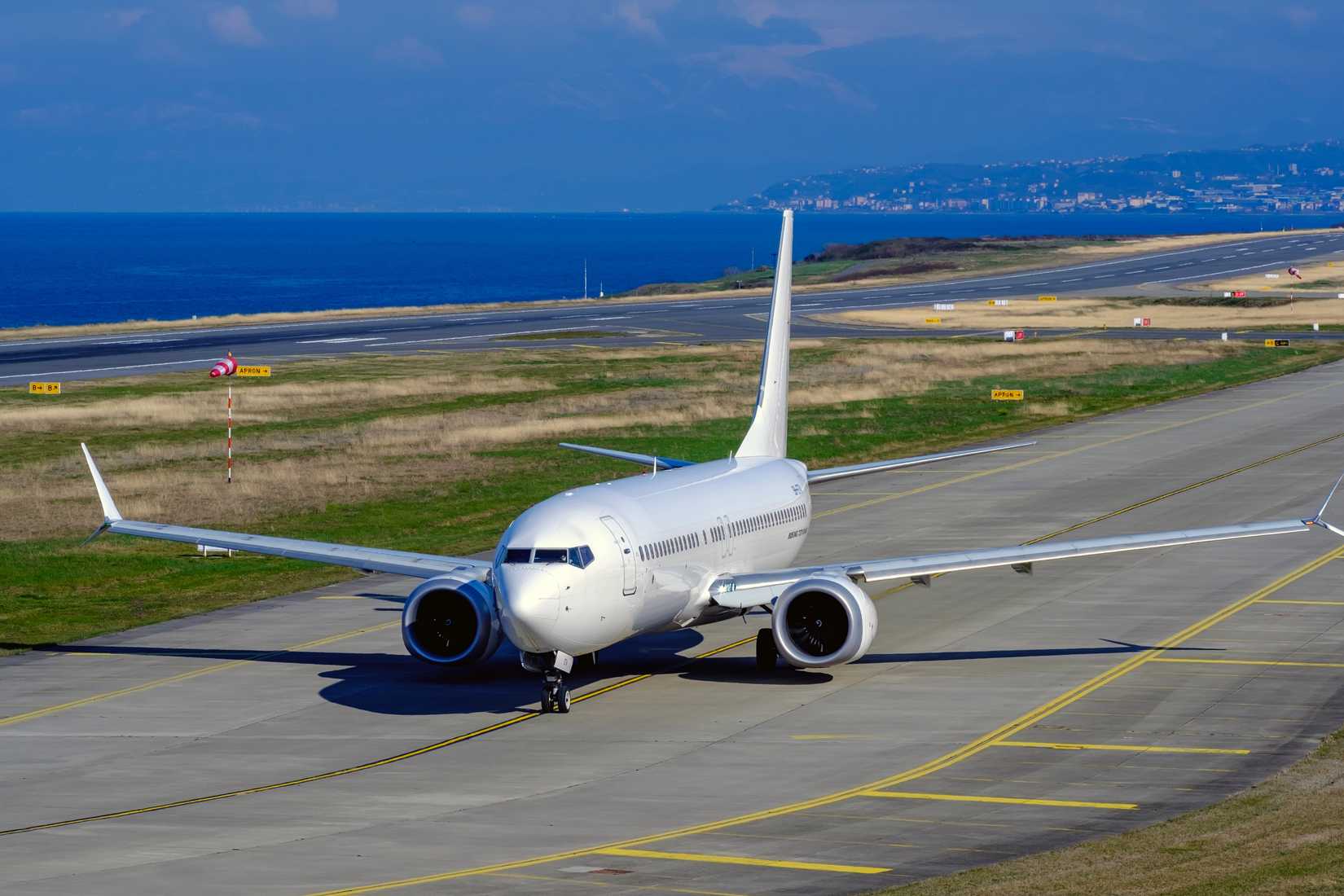 A white unbranded Boeing 737 MAX is taxiing on the runway at the coastal Trabzon Airport