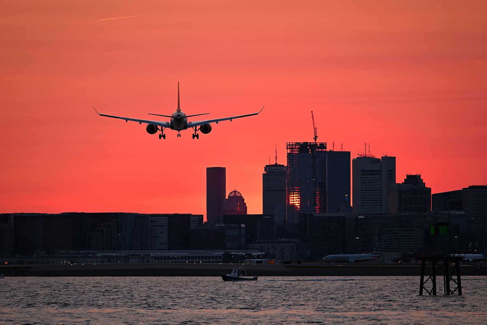 Airbus A220 on final approach to Runway 27 at Boston during sunset