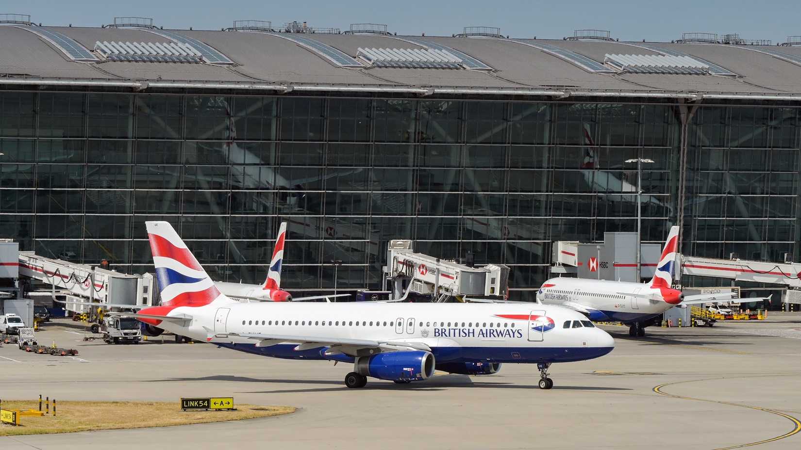 Aribus A320 (registration G-EUUE) operated by British Airways taxiing for take off in front of Terminal 5 at London Heathrow airport