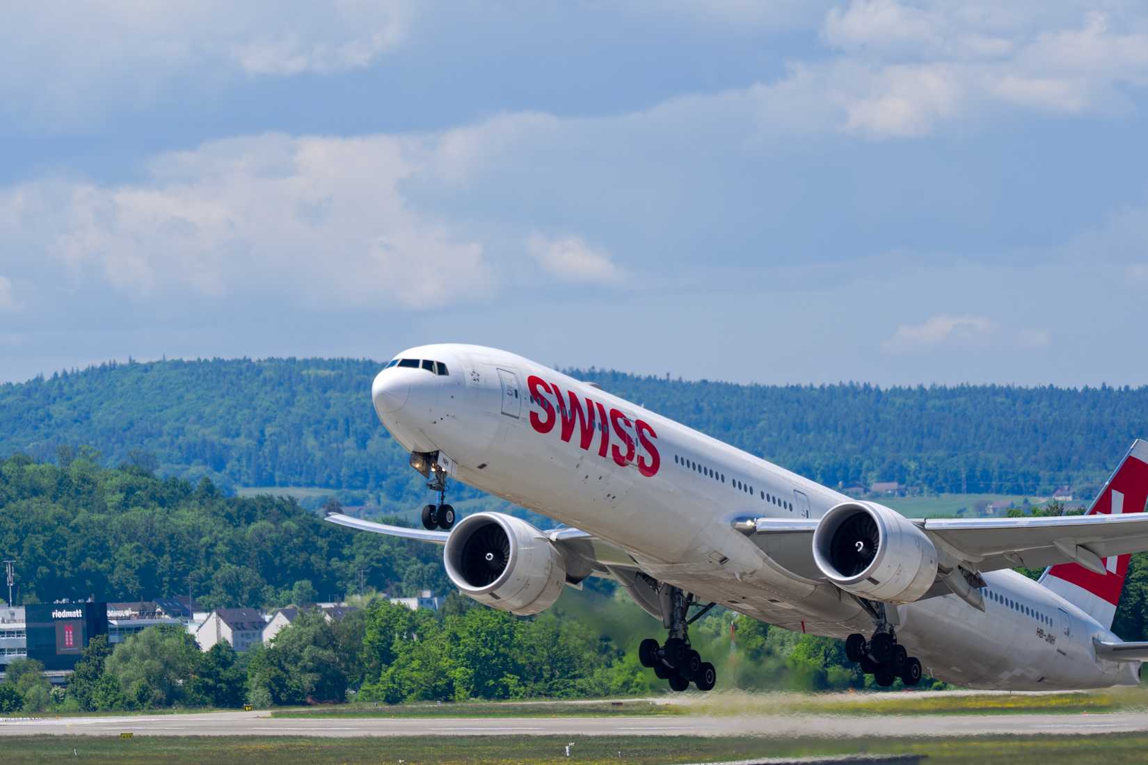 Boeing 777-300ER registration HB-JNH taking off from Swiss Airport Zürich Kloten on a sunny spring day.